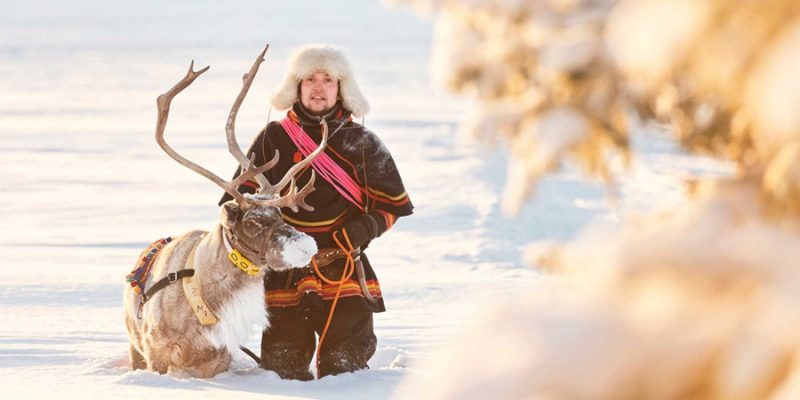 Sami Kultur in Lappland Mann mit Rentier im Winter