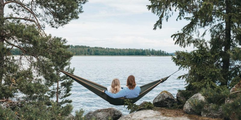 Paar sitzt auf Hängematte in Skandinavien vor einem See