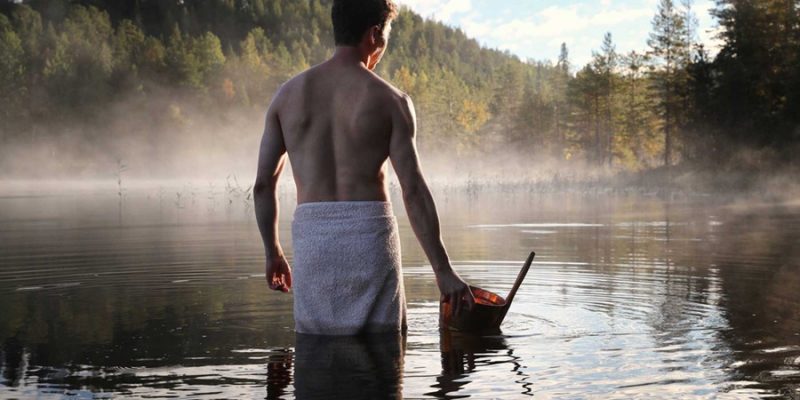 Mann mit Handtuch im See nach der Sauna in Finnland