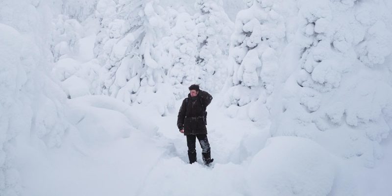 Mann steht im Schnee in Lappland im Winter