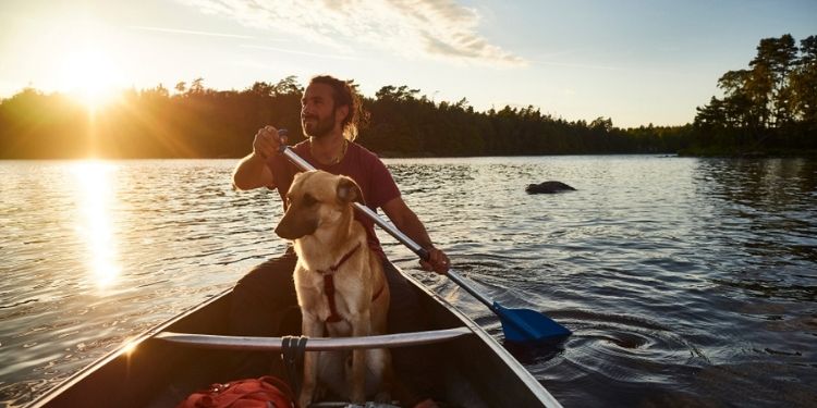 Mann-mit-Hund-auf-Boot-in-Skandinavien-Reisen-mit-Nordic