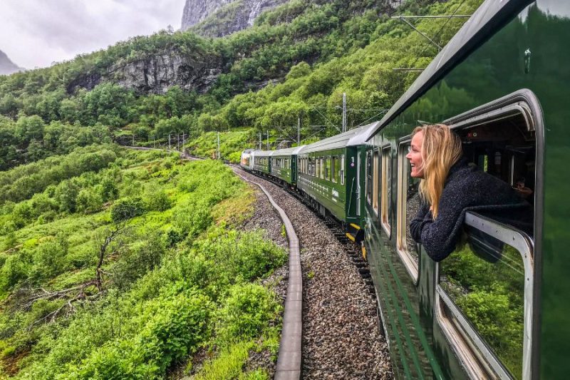 Frau guckt-aus-dem-Fenster-in-der-Flamsbana-Zugfahrt-in-Norwegen-Torild Moland - TravelStock-VisitNorway