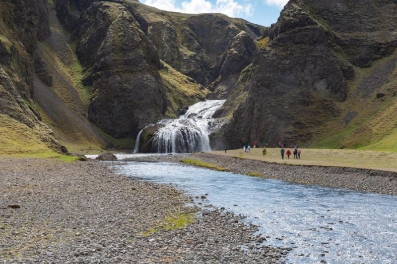 Reisende-an-einem-Wasserfall-auf-Island-Urlaub-mit-Nordic-Skandinavien-Spezialist-©Benny-Petak